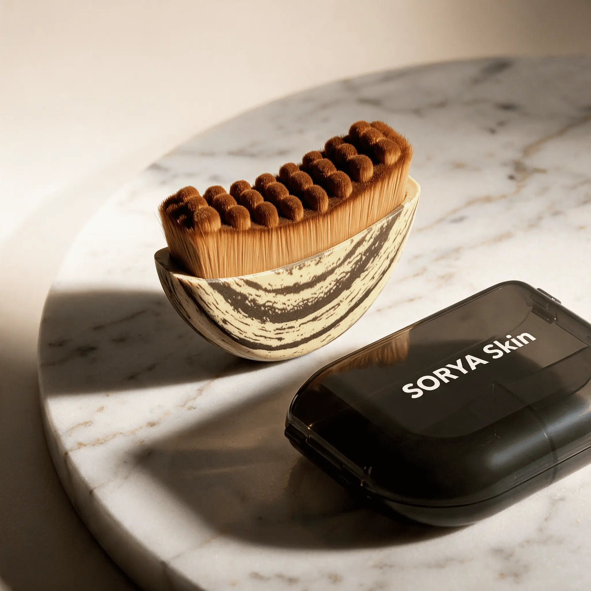 Sorya Velour Brush, brosse de drainage lymphatique visage, avec son étui sur un plateau en marbre